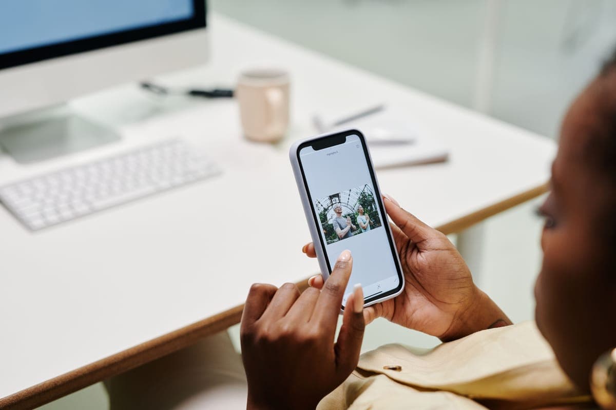 A phone showing a smart-home app beside a few smart devices on a clean desk.