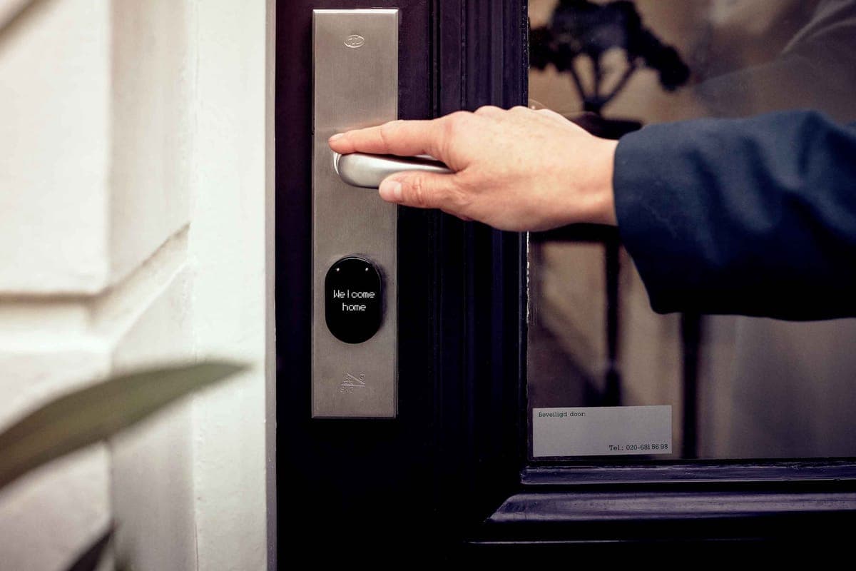 A smart deadbolt with a touchscreen keypad on a modern front door in daylight.